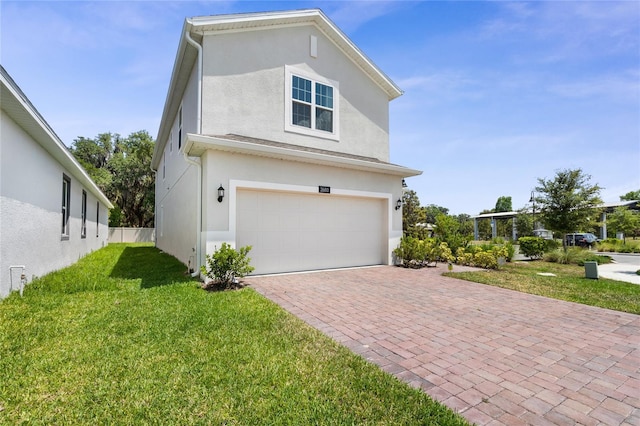 view of side of home with decorative driveway, a garage, stucco siding, and a yard