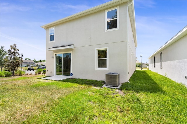 back of property with a yard, stucco siding, and cooling unit