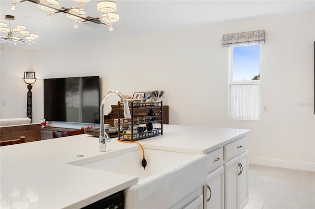 clothes washing area with an inviting chandelier, a sink, and baseboards