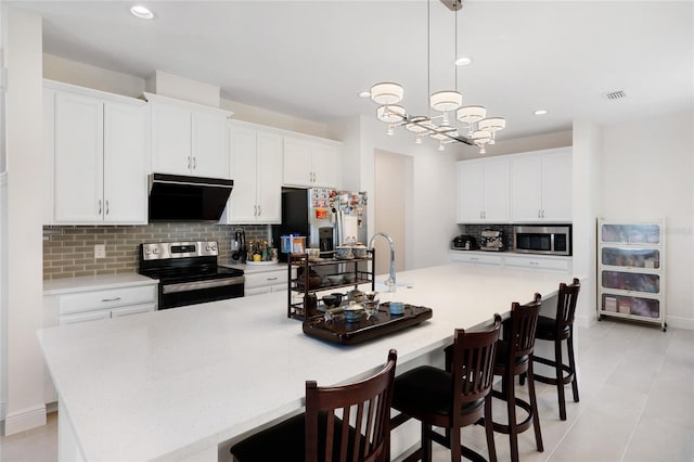 kitchen with appliances with stainless steel finishes, visible vents, light countertops, backsplash, and a spacious island