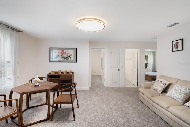 living area with visible vents, baseboards, and light colored carpet