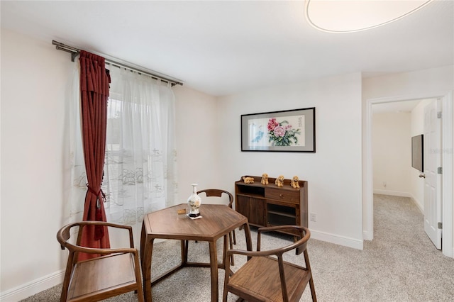 dining room featuring baseboards and light carpet