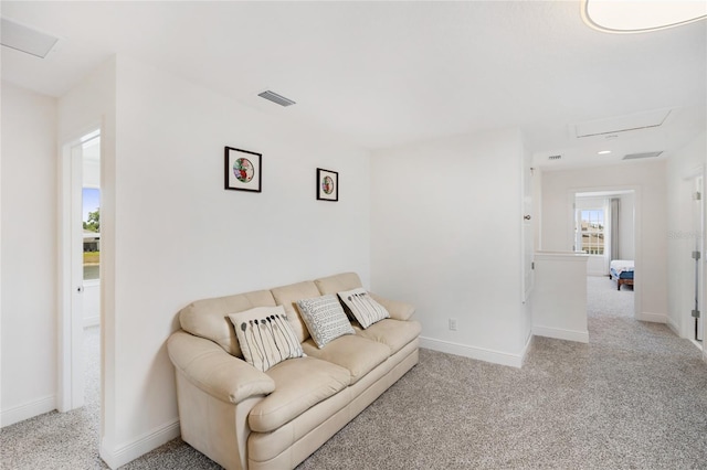 living area featuring visible vents, attic access, and light carpet