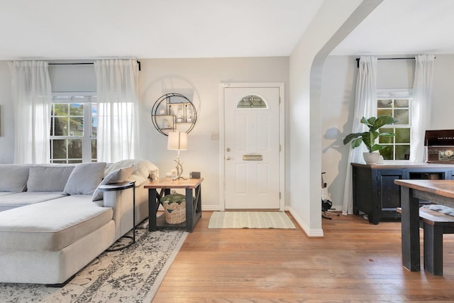 foyer with arched walkways, baseboards, and hardwood / wood-style floors