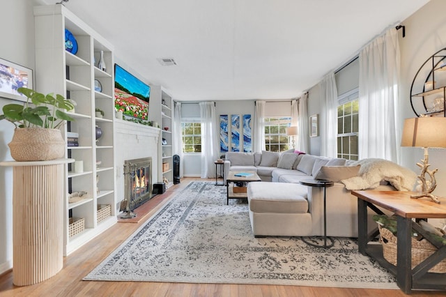 living area featuring a glass covered fireplace, wood finished floors, and visible vents