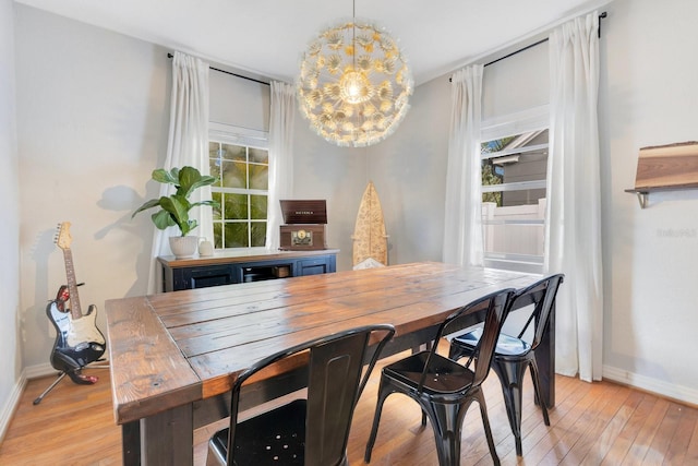dining space featuring light wood-style floors, baseboards, and a notable chandelier