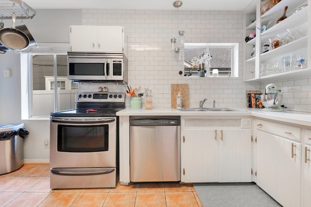 kitchen featuring backsplash, appliances with stainless steel finishes, a sink, light countertops, and light tile patterned flooring