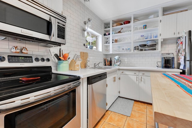 kitchen with appliances with stainless steel finishes, tasteful backsplash, a sink, light tile patterned floors, and light countertops