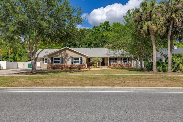 ranch-style house with a porch, a front lawn, fence, and driveway