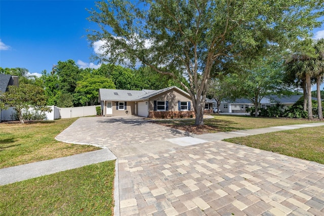 view of front facade featuring fence, an attached garage, decorative driveway, and a front yard