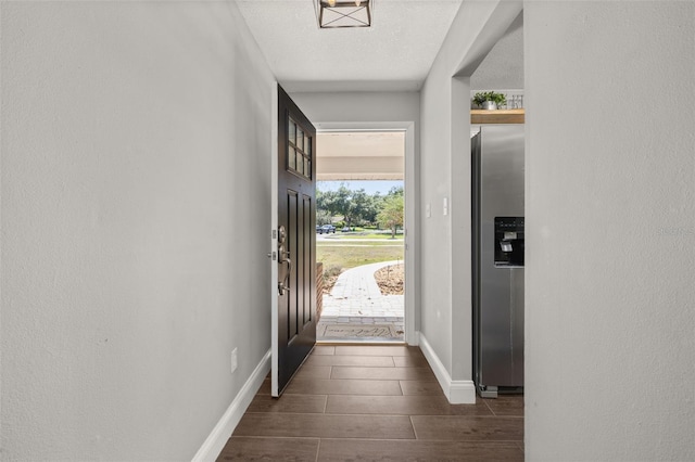 entryway featuring dark wood-style flooring, baseboards, and a textured ceiling