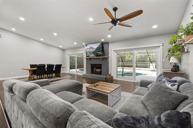 living area featuring a brick fireplace, recessed lighting, a ceiling fan, and wood finished floors