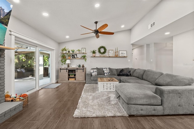 living room featuring a ceiling fan, visible vents, dark wood-style floors, and vaulted ceiling