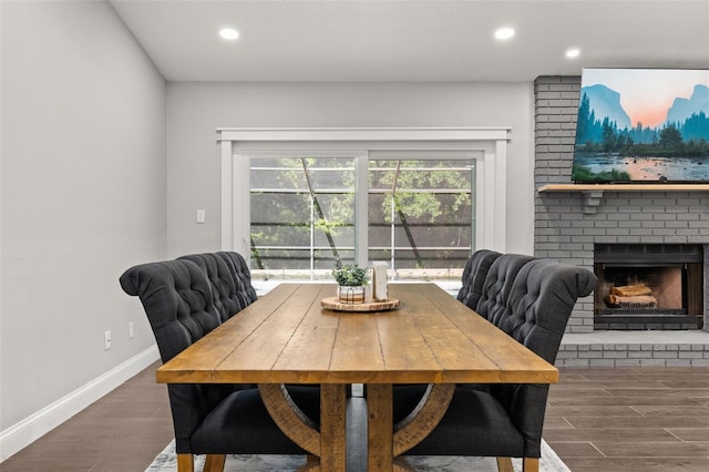 dining area with a brick fireplace, recessed lighting, baseboards, and wood finished floors