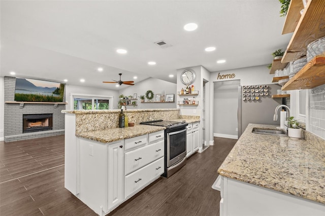 kitchen featuring open shelves, a peninsula, dark wood-style floors, a sink, and stainless steel range with electric cooktop