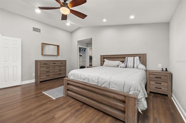 bedroom with a walk in closet, a ceiling fan, wood finished floors, vaulted ceiling, and visible vents
