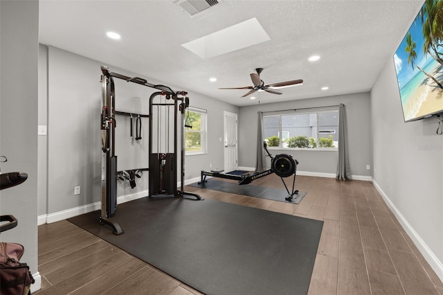 workout area with a skylight, recessed lighting, wood finished floors, and visible vents