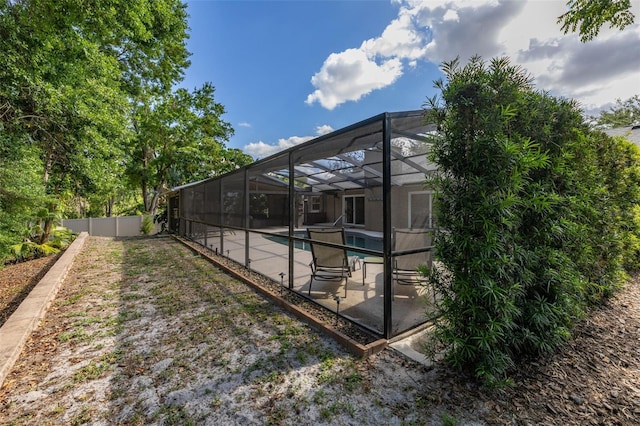 exterior space featuring glass enclosure, a patio, fence, and an outdoor pool