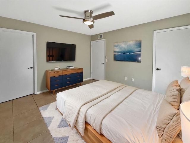 bedroom featuring a ceiling fan, visible vents, and light tile patterned floors