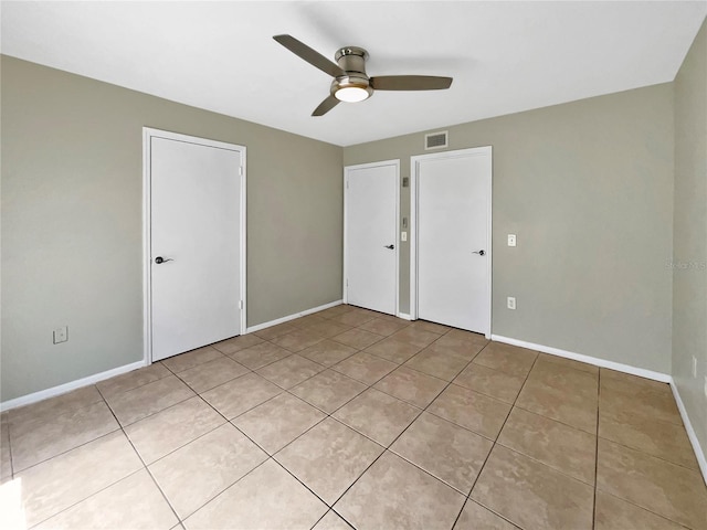 unfurnished bedroom with ceiling fan, baseboards, visible vents, and light tile patterned floors