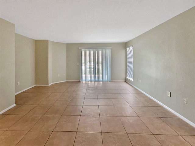 spare room with light tile patterned flooring and baseboards