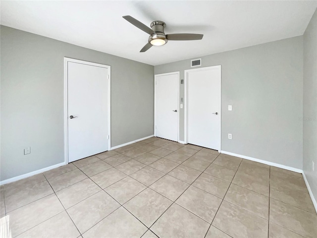 unfurnished bedroom featuring a ceiling fan, baseboards, visible vents, and light tile patterned flooring