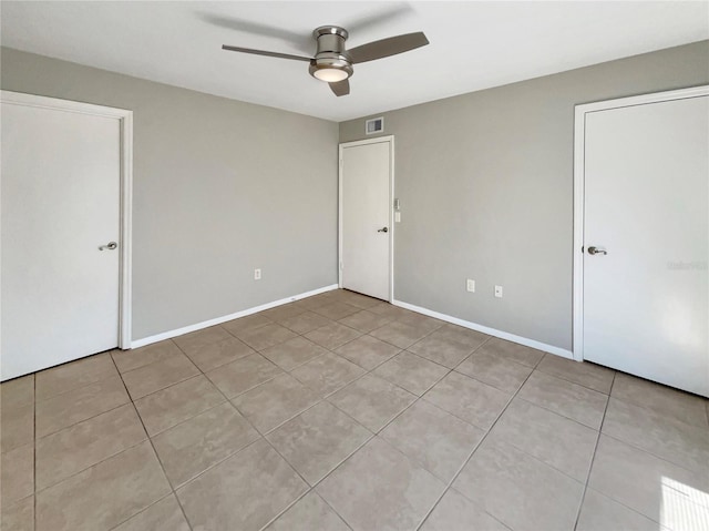 unfurnished bedroom with visible vents, a ceiling fan, baseboards, and light tile patterned floors