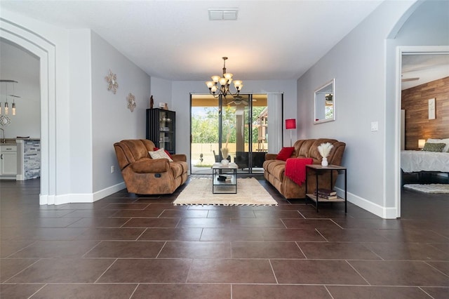 living area with arched walkways, a chandelier, baseboards, dark tile patterned floors, and visible vents