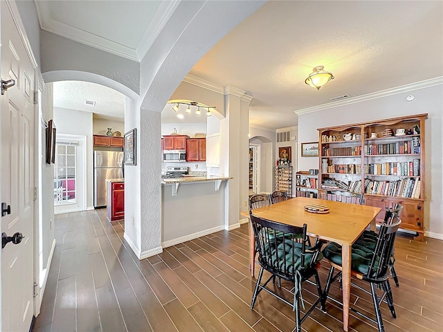 dining room featuring dark wood-style flooring, arched walkways, visible vents, and ornamental molding