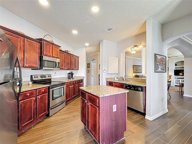 kitchen with stainless steel appliances, wood finish floors, visible vents, and dark brown cabinets