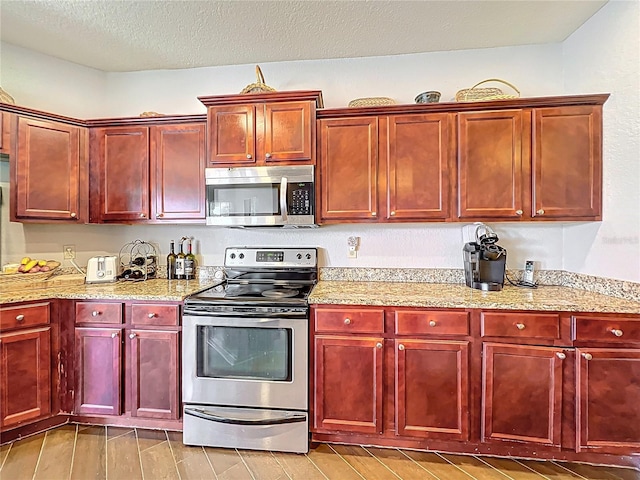 kitchen with light stone counters, dark brown cabinets, and stainless steel appliances