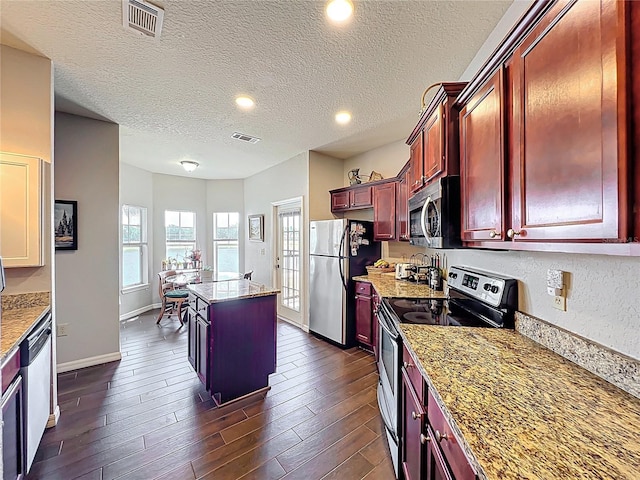 kitchen with visible vents, a kitchen island, stainless steel appliances, and dark brown cabinets