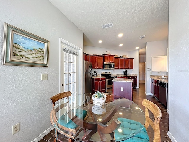 dining space featuring baseboards, a textured wall, a textured ceiling, and visible vents