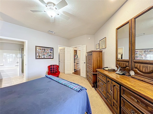 bedroom with light carpet, ensuite bath, a textured ceiling, a ceiling fan, and visible vents