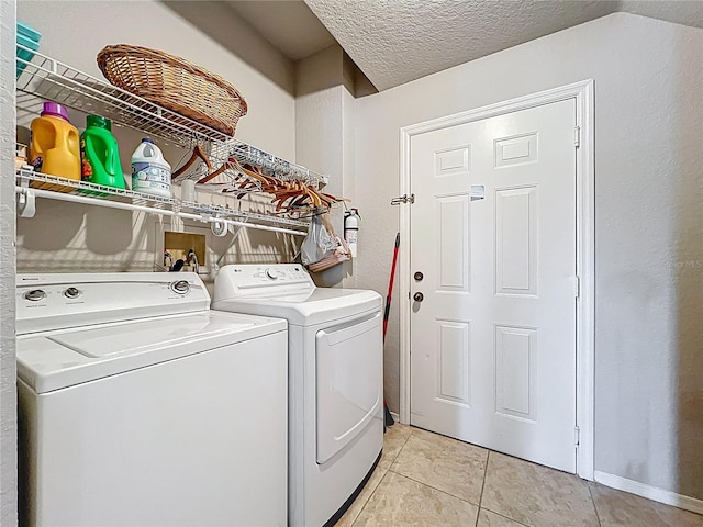 laundry area featuring independent washer and dryer, a textured ceiling, laundry area, and light tile patterned floors