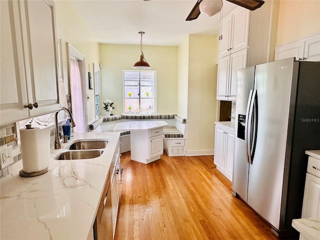 kitchen with a peninsula, stainless steel fridge, a ceiling fan, a sink, and white cabinets