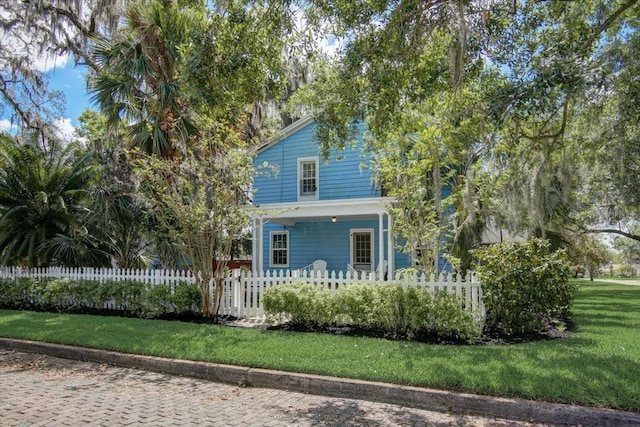 view of front of home featuring a front yard, a fenced front yard, and covered porch