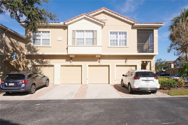 multi unit property featuring driveway, a tile roof, and stucco siding