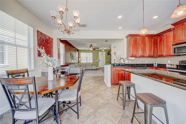 7348 Yoder St, Windermere, FL 34786 - kitchen with pendant lighting, decorative backsplash, a kitchen breakfast bar, ceiling fan with notable chandelier, and stainless steel appliances