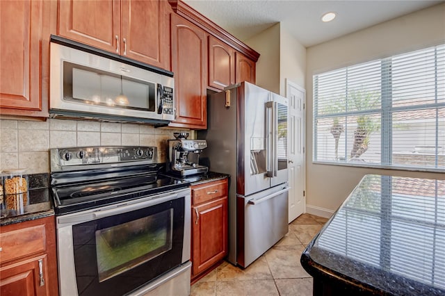 7348 Yoder St, Windermere, FL 34786 - kitchen with decorative backsplash, baseboards, dark stone countertops, light tile patterned floors, and stainless steel appliances