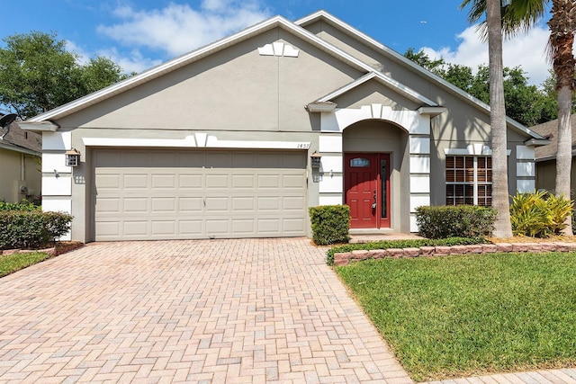 single story home with an attached garage, decorative driveway, and stucco siding