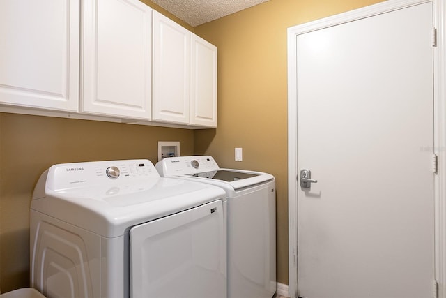 clothes washing area with independent washer and dryer, a textured ceiling, and cabinet space
