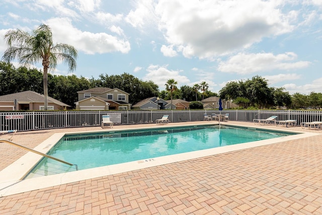 community pool with fence, a residential view, and a patio area