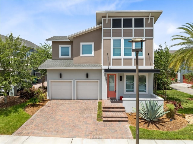 8263 Bellow St, Orlando, FL 32827 - view of front of house featuring a garage, stucco siding, a shingled roof, and decorative driveway