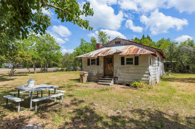 rear view of property with a lawn, entry steps, and a chimney