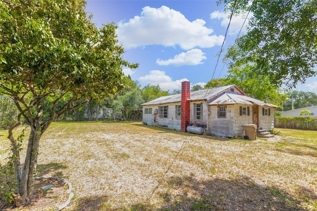 rear view of property with a yard, a chimney, and entry steps