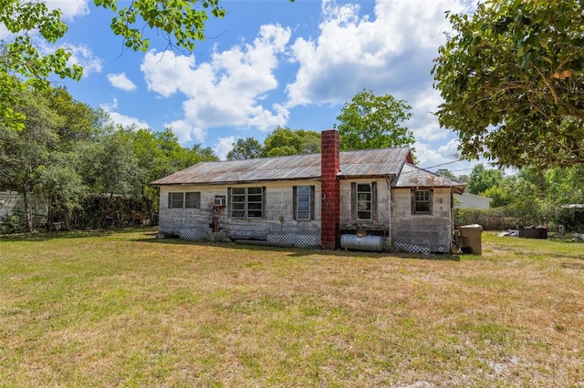 back of house with a lawn, a chimney, and stone siding