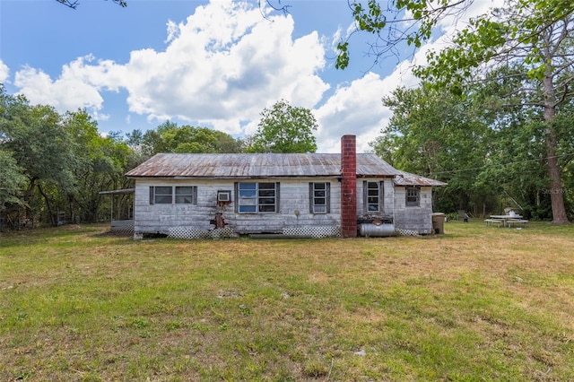 rear view of property featuring a chimney and a lawn