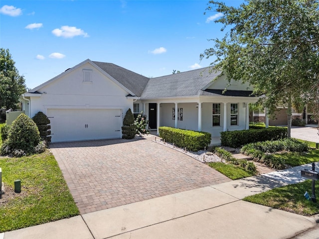 ranch-style house featuring a porch, decorative driveway, an attached garage, and stucco siding