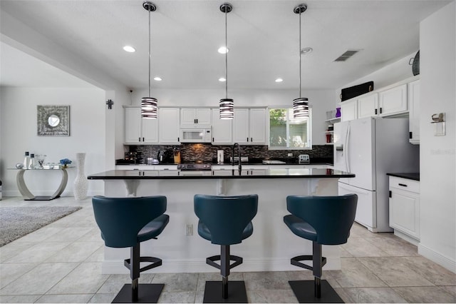 kitchen with dark countertops, decorative backsplash, and white appliances